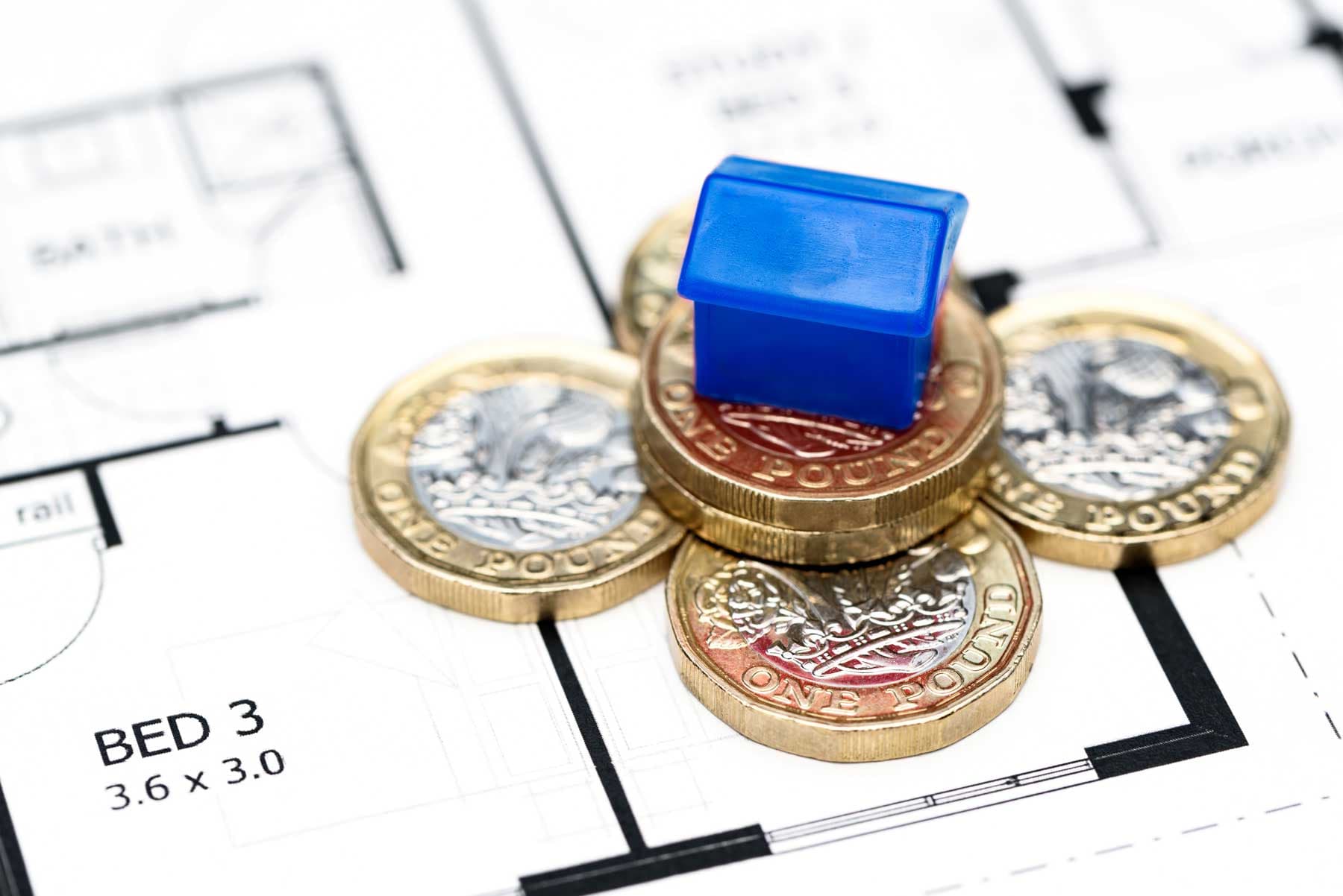 Model house and pound coins on a property floor plan